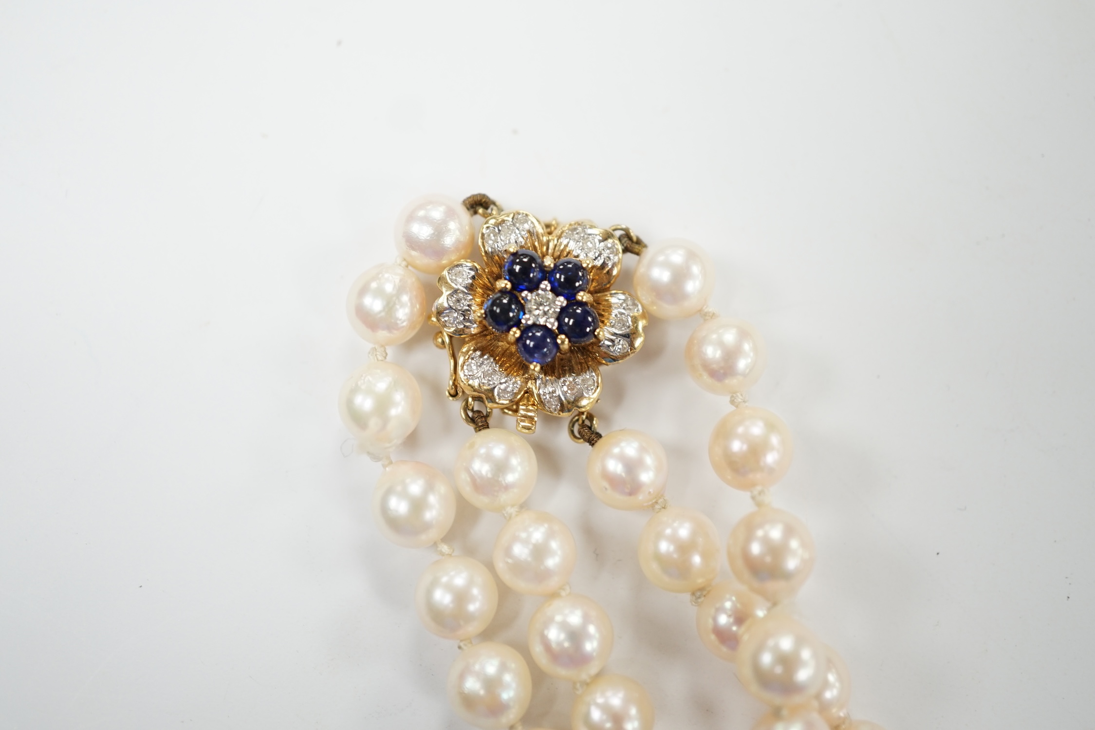A double strand cultured pearl necklace, with cabochon sapphire and diamond chip cluster set 14k clasp, 44cm. Condition - good